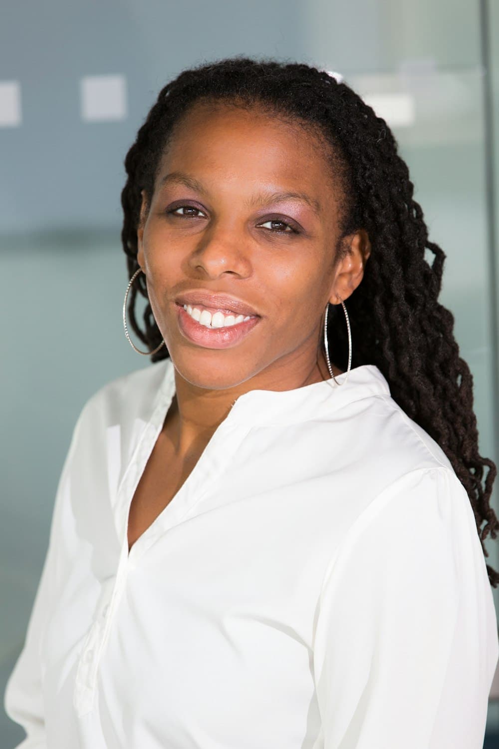 Portrait of a smiling woman with long braids in a white top