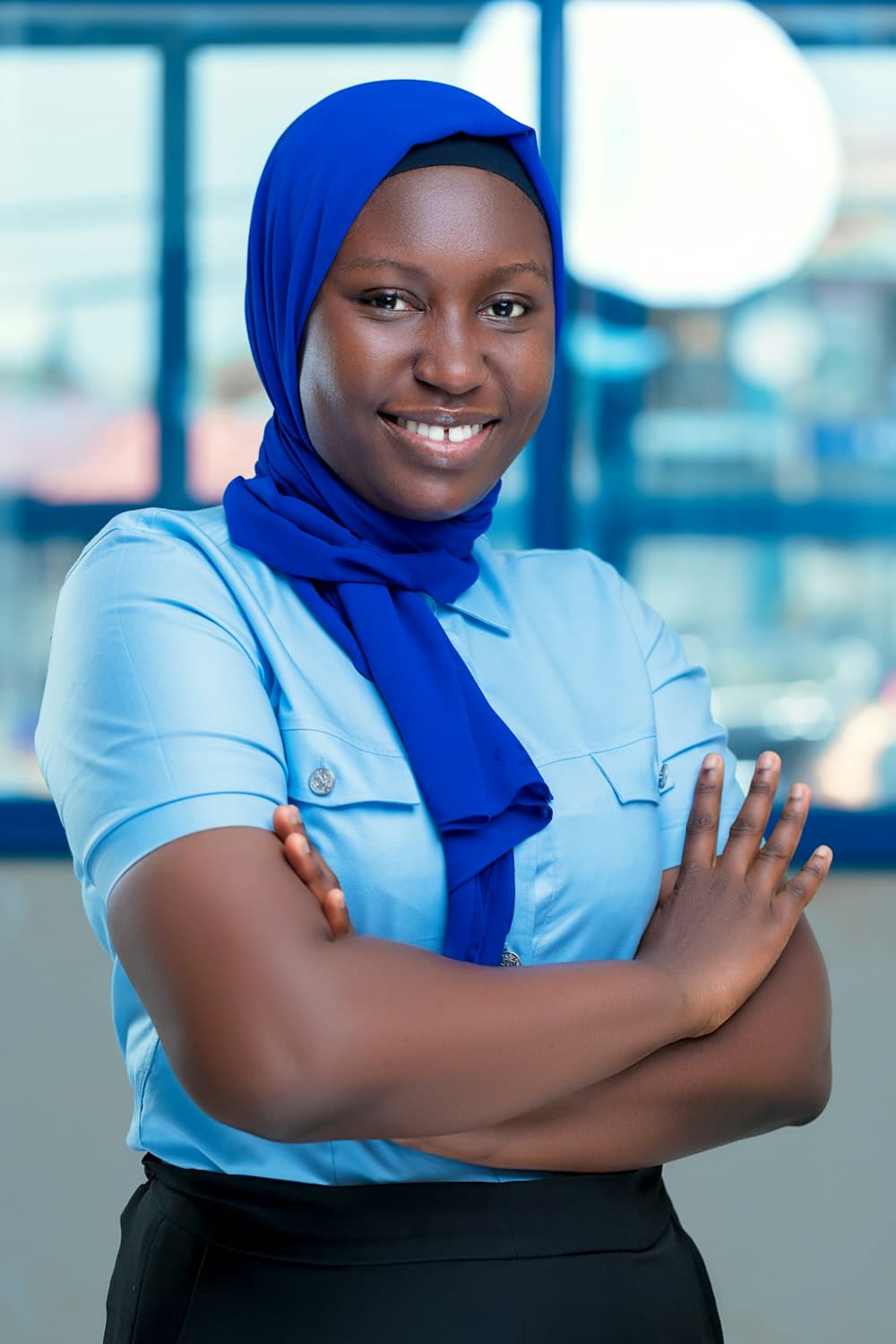 Portrait of a smiling woman wearing a blue headscarf and light blue shirt