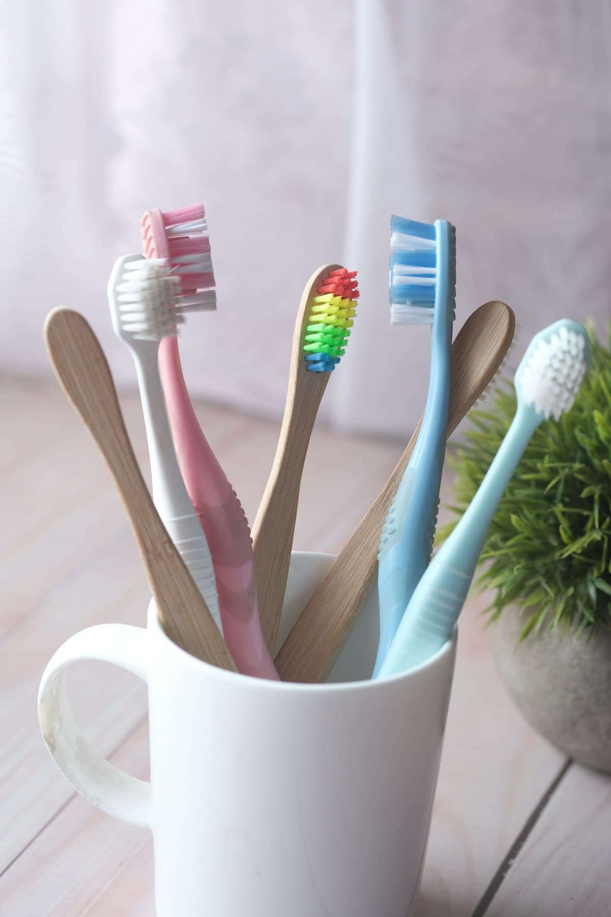Several colourful toothbrushes standing in a white cup