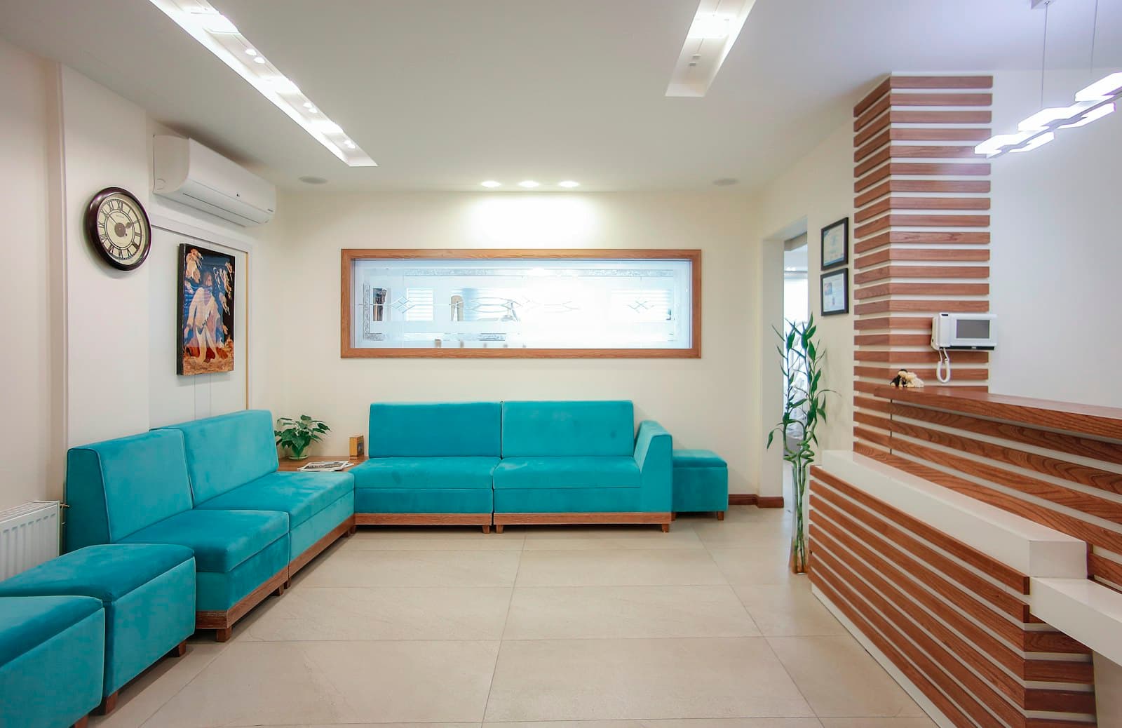 A calm clinic lounge with teal sofas, wooden accents and soft lighting